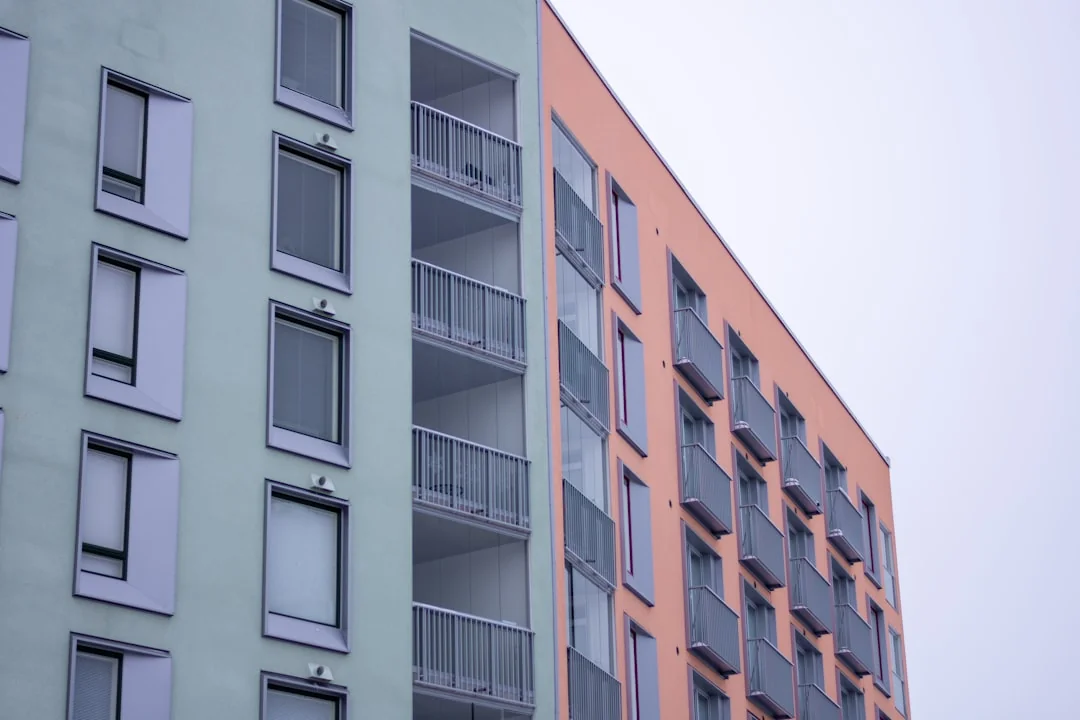 Two workers clean windows on a tall office building in a city setting.